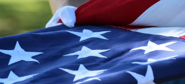 Close-up of an American flag with white stars on blue fabric, partially folded.