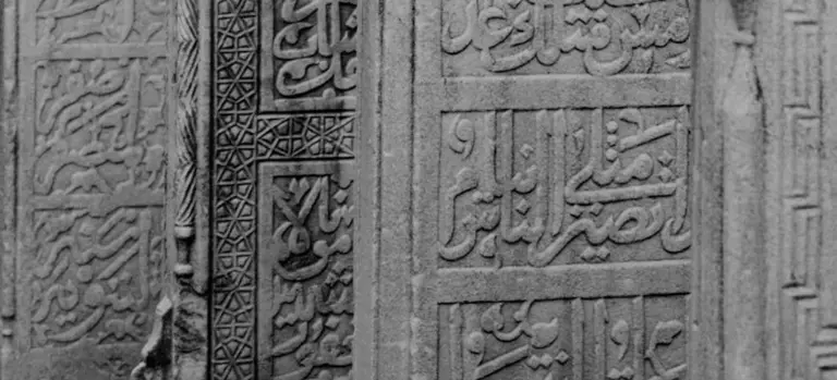 Carved stone wall with intricate Arabic calligraphy.