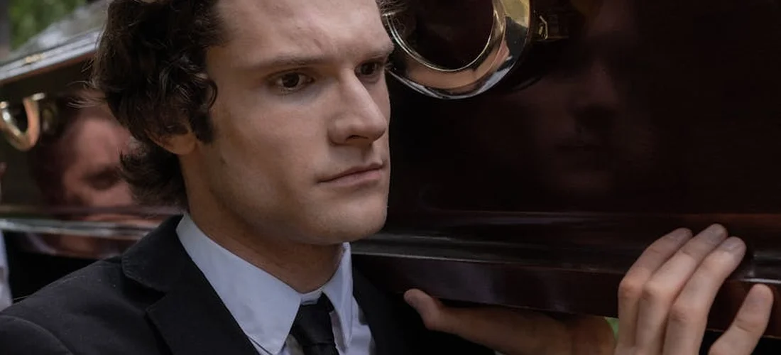 Solemn man in a suit standing beside a hearse, illustrating funeral planning and prepayment.
