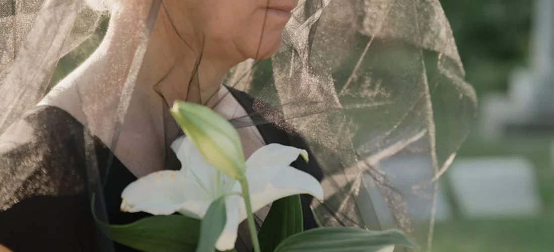 Close-up of a bride holding a white lily bouquet behind a delicate veil
