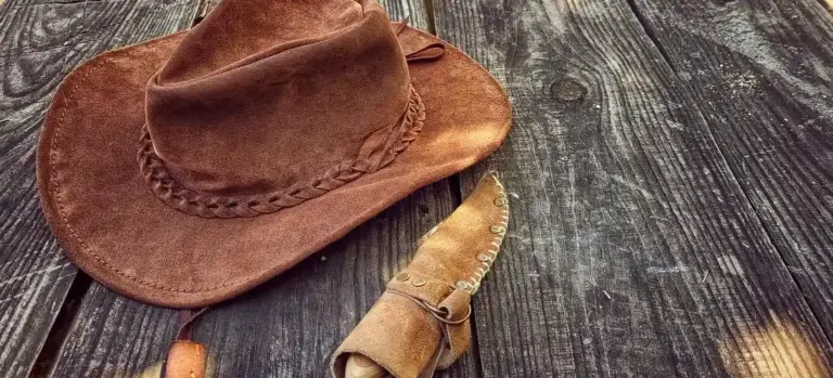 A brown cowboy hat resting on dark, weathered wooden planks