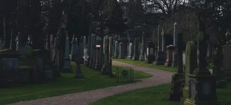 Gravestones and a winding path in a quiet cemetery under an overcast sky
