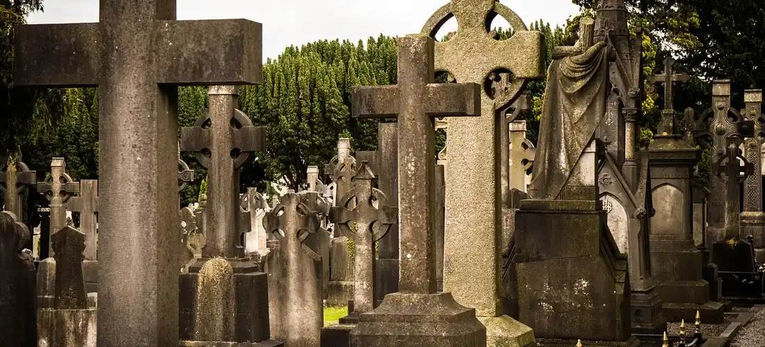 Rows of weathered gravestones and crosses in a quiet cemetery