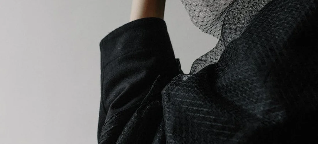 Close-up of dark fabric and a sheer veil, conveying a somber, understated mood.