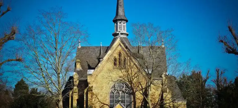 Stone church with a tall steeple against a clear blue sky