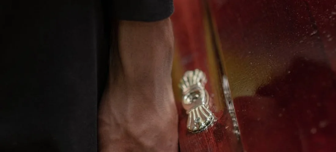 Close-up of a polished metal handle on a wooden casket