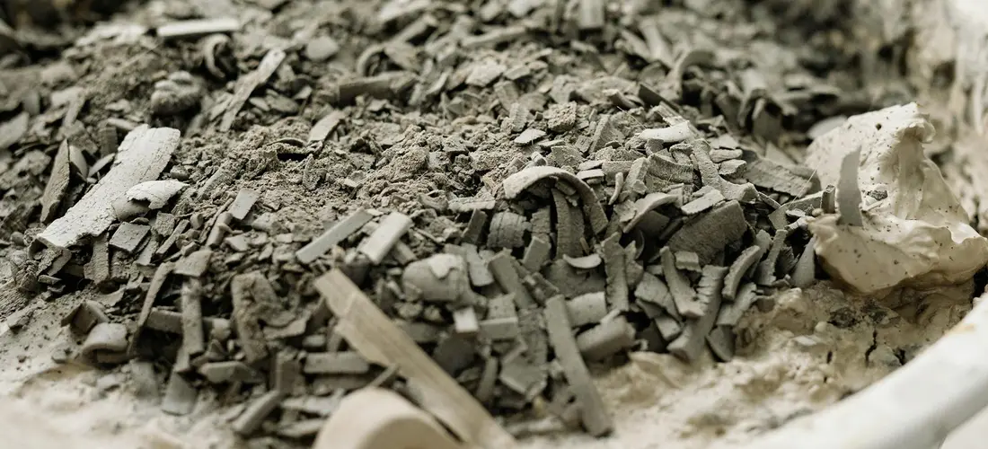 Close-up of cremation ashes showing dark, granular fragments and small chips with a gritty, sand-like texture.