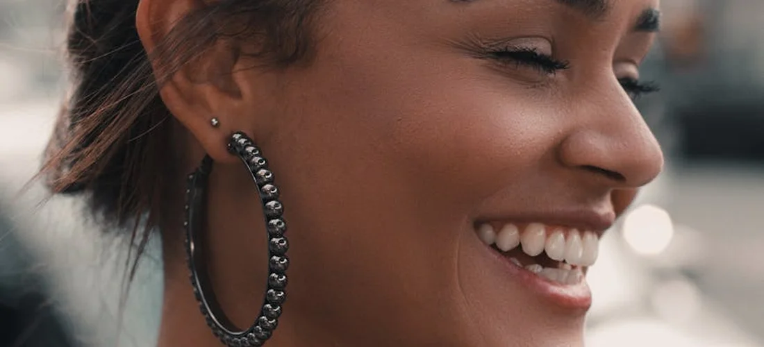 Close-up of a smiling person wearing a large hoop earring.