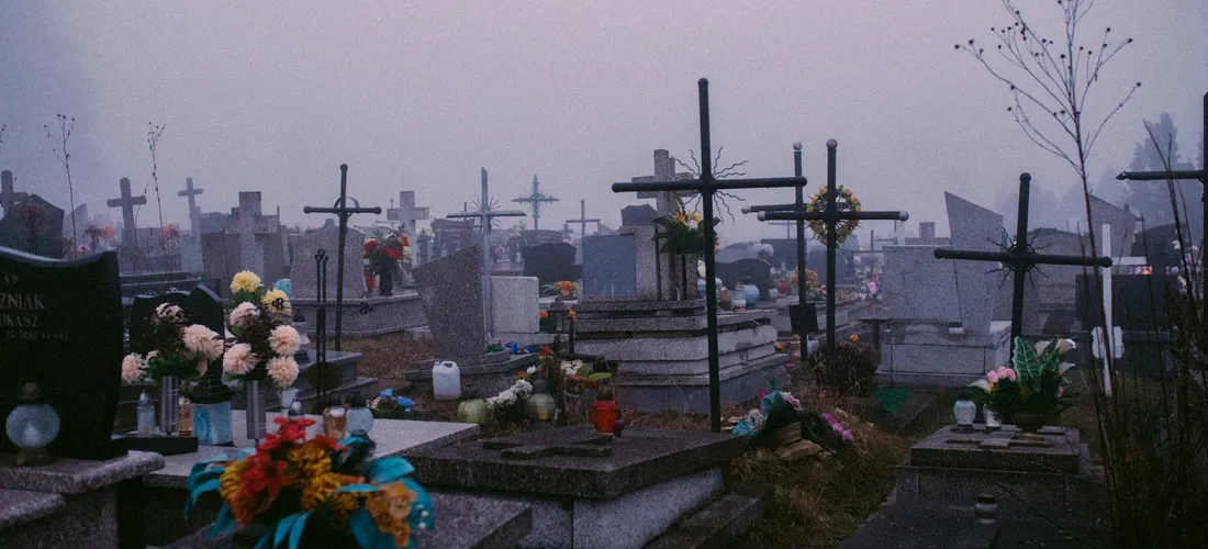 Gravestones and crosses in a cemetery with flowers, illustrating the land-based context of laws governing scattering cremated remains.