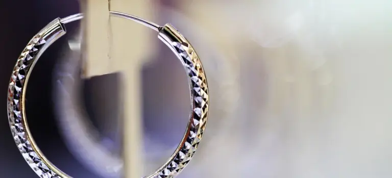 Close-up photograph of a diamond-studded circular jewelry piece with a blurred background, illustrating keepsake jewelry that may accompany a body for cremation.