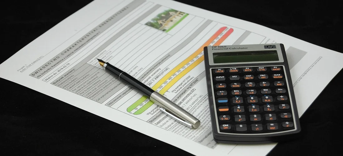 Close-up of a legal document with a pen and a calculator on a dark surface, representing consent and authorization for cremation.