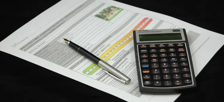 Pen resting on official forms with a calculator nearby, representing the administrative steps involved in death certificate processing through a funeral home.