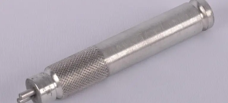 Metal syringe-like embalming tool with a knurled grip and slender cylindrical body