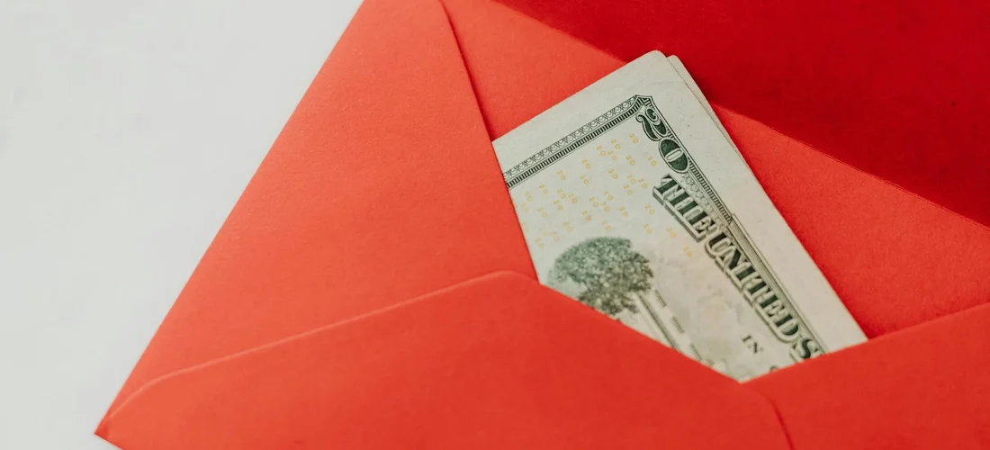 Red envelope with a folded hundred-dollar bill inside