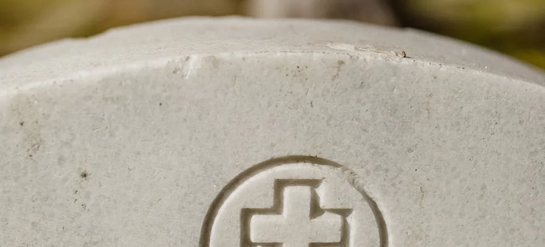 Close-up of a circular medical cross emblem on a light stone surface