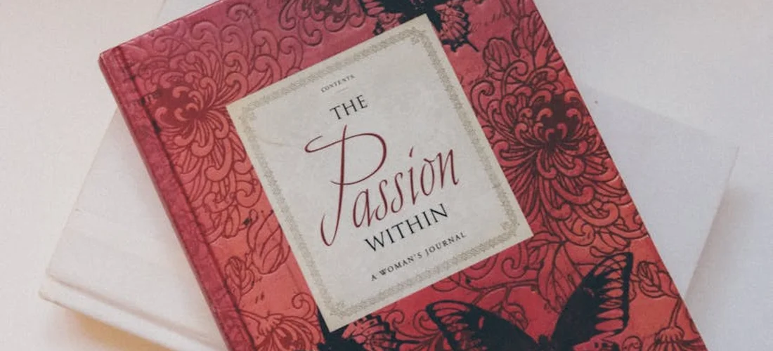 Red ornate funeral booklet with a white label on the cover that reads The Passion Within.