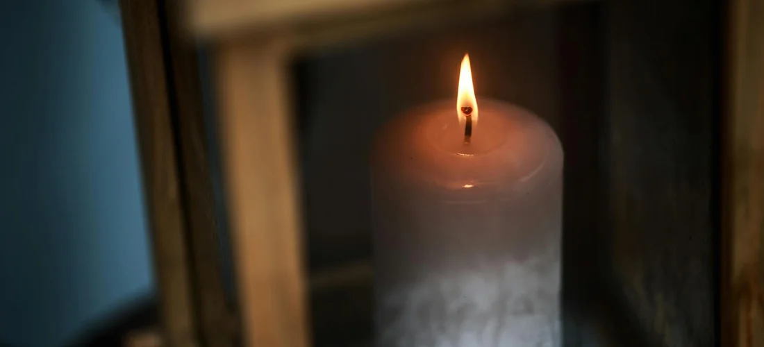 A lit candle inside a lantern, symbolizing remembrance and funeral planning.