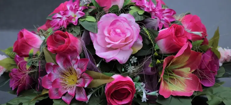 Close-up of a pink flower bouquet featuring roses and lilies, arranged for a funeral tribute.