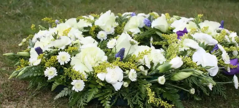 White and purple funeral flower arrangement on the grass