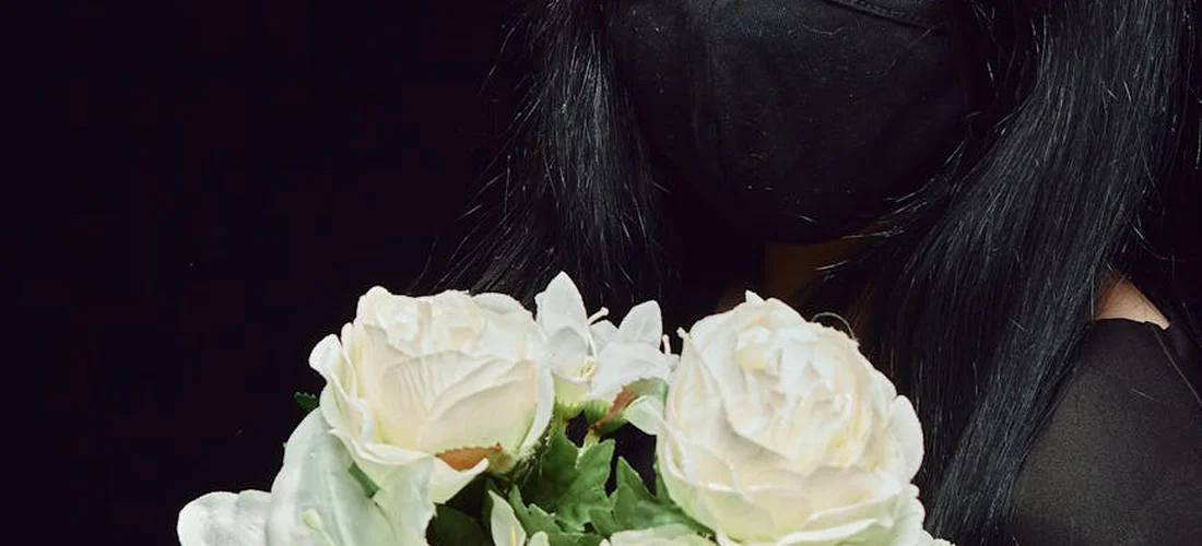 A bouquet of white roses with greenery set against a dark background.