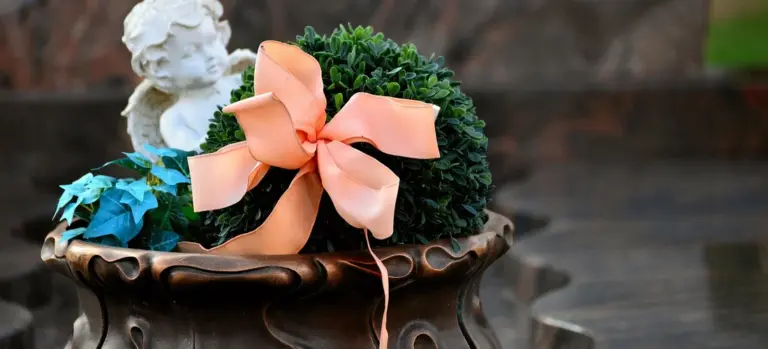 Decorative potted plant with a peach ribbon and a small white angel statue