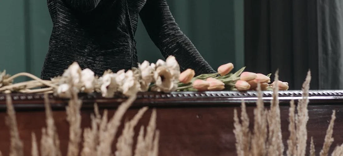 A funeral casket with floral tributes in front, prepared for a service.