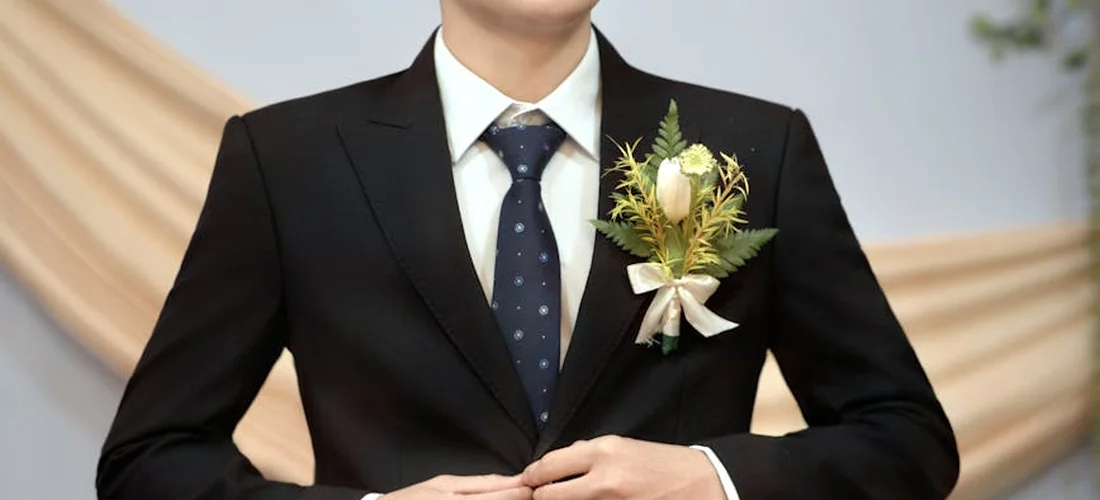 Man in a black suit with a boutonnière at a funeral, representing formal attire and the consideration of cultural and religious dress norms.