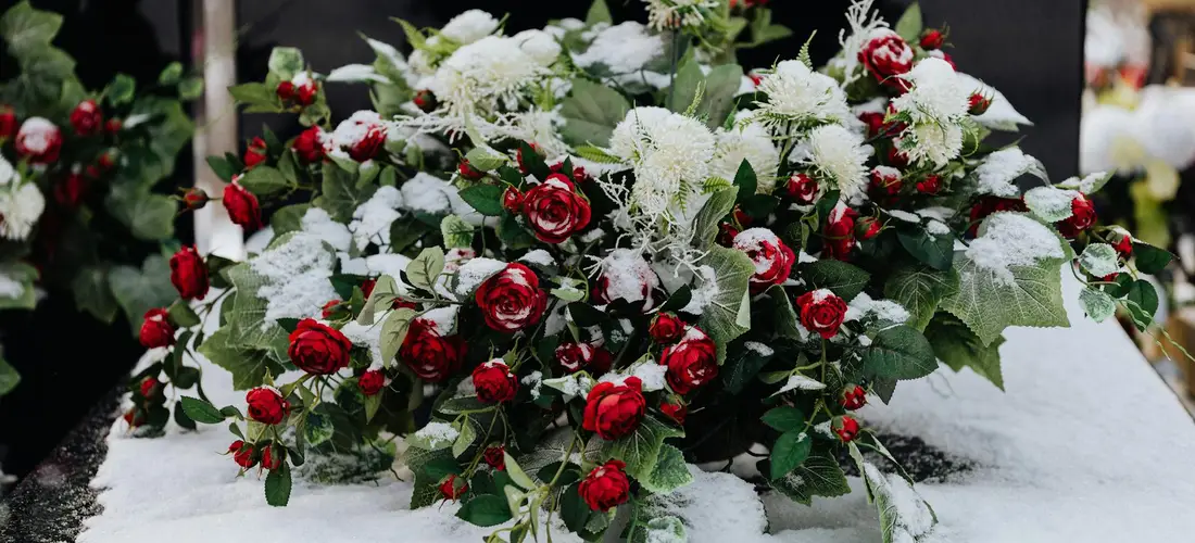 Bouquet of red roses and white filler flowers arranged as a funeral centerpiece.