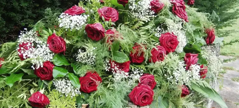 Bouquet of red roses with white filler flowers and greenery, a traditional funeral arrangement