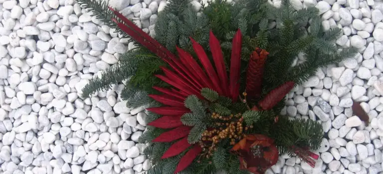 Floral arrangement resting on white pebbles, a typical funeral decor scene.