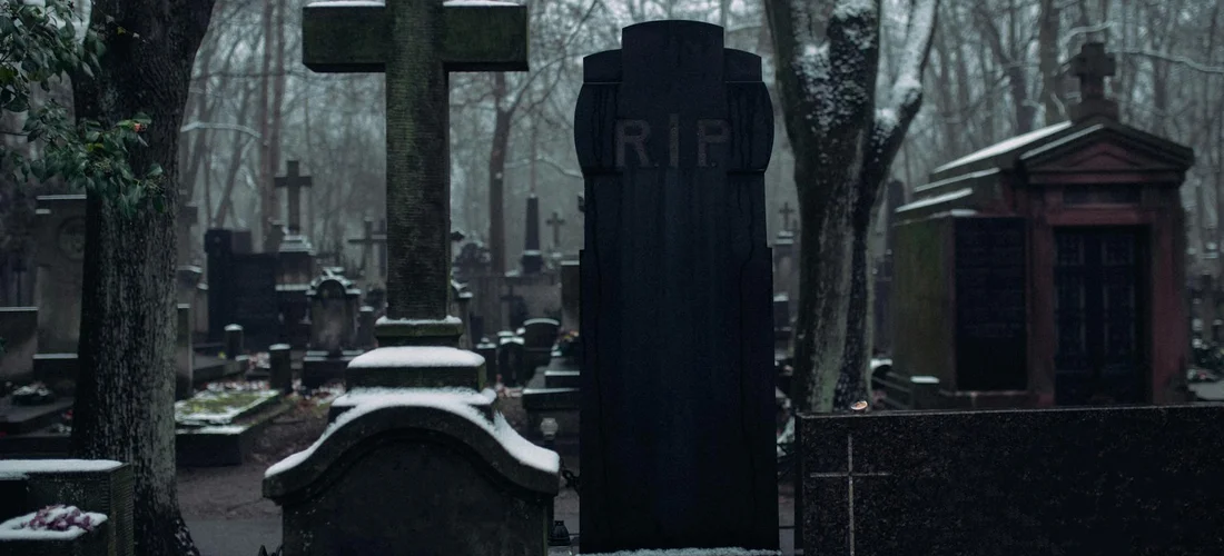 Gravestones in a cemetery with a large cross and a moody, subdued atmosphere