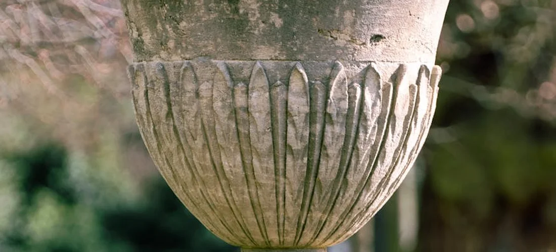 Weathered stone garden urn in a tranquil outdoor setting