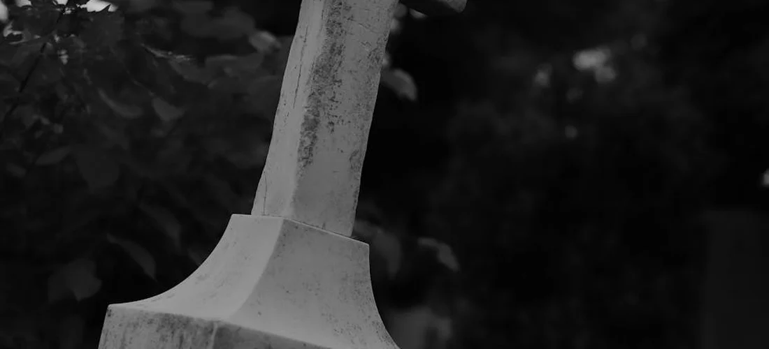 Close-up of a gravestone with a blurred natural background, conveying reflection and remembrance.