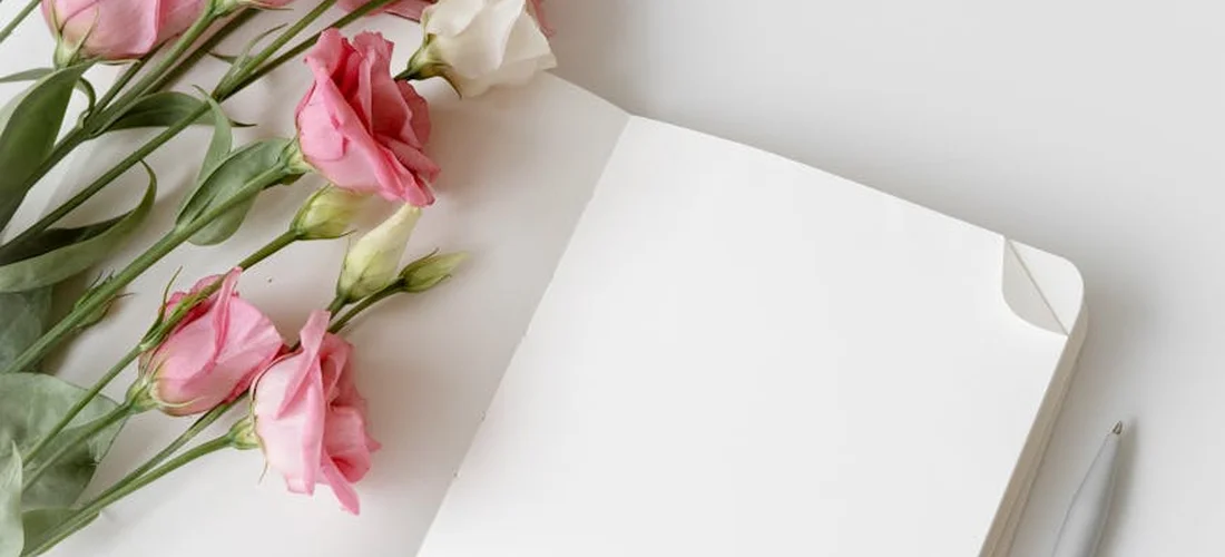 Open blank guest book with pink roses on a white desk