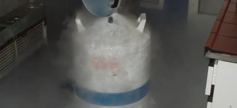 A large gas cylinder in a facility emitting visible vapor, illustrating storage and handling of embalming-related chemicals