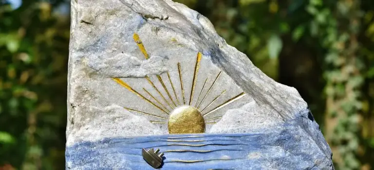 Stone memorial with a sun rising over water motif, symbolizing remembrance at a funeral.