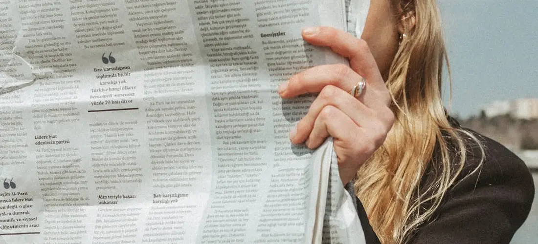 Person holding and reading a newspaper outdoors
