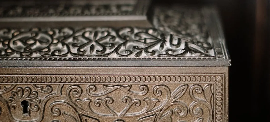 Close-up of an ornate metal box with intricate floral engravings and a small keyhole, symbolizing secure storage.
