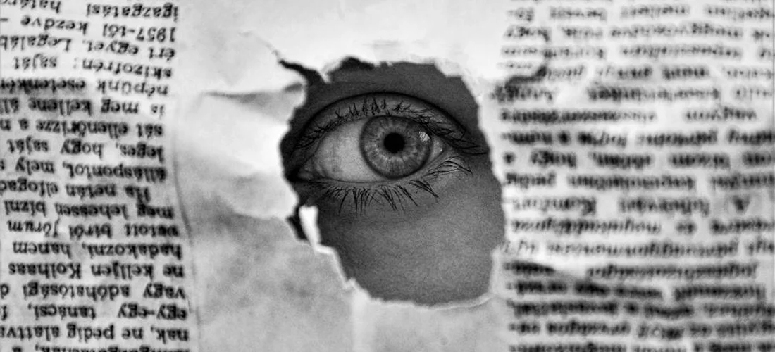 Close-up of an eye peeking through torn newspaper pages, symbolizing regional obituary searches