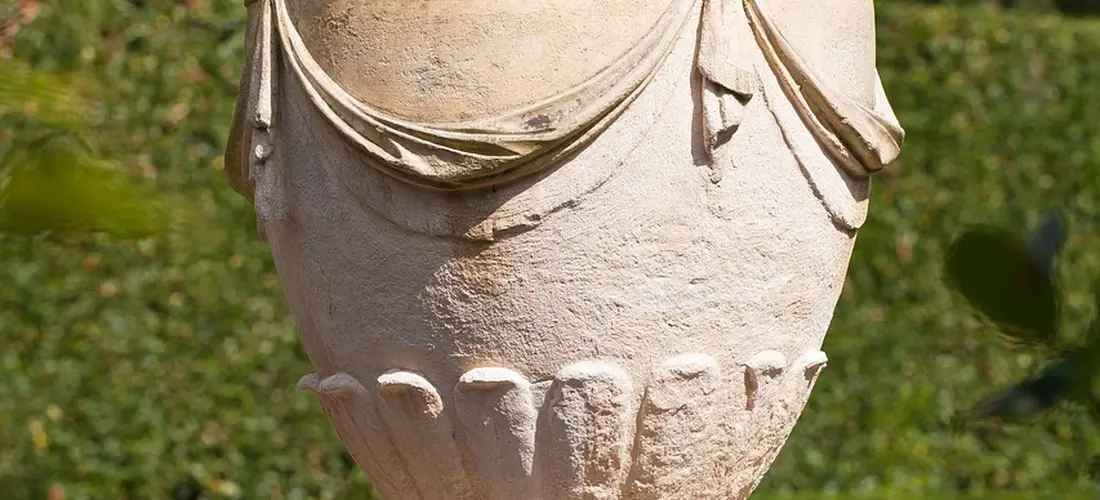 Weathered stone urn in a garden setting.