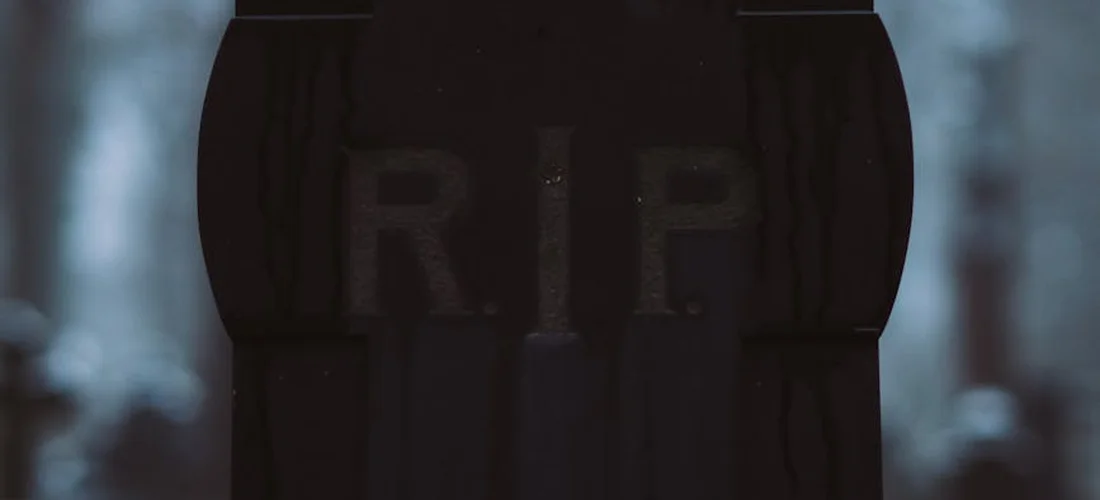 Close-up of a dark tombstone engraved with 'RIP' in a cemetery