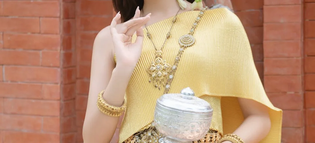 Person in a gold outfit holding a decorative metal urn, illustrating nontraditional ways to store cremated ashes.