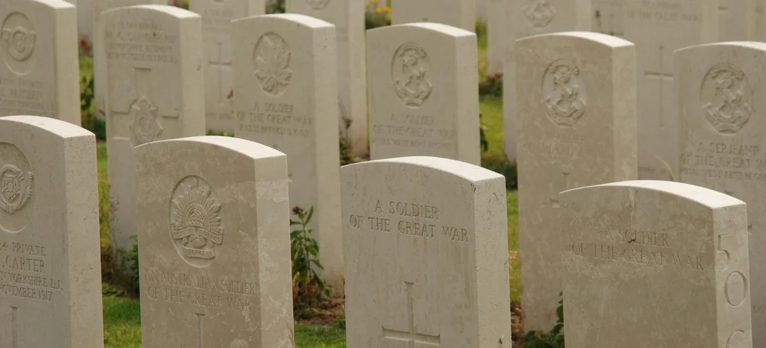 Rows of white headstones in a VA National Cemetery with green grass between markers