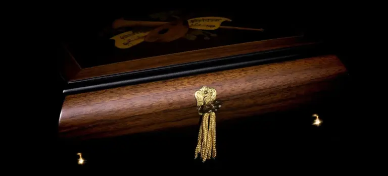 Closed wooden casket with a gold tassel against a dark background