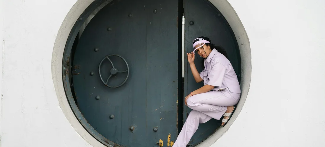 Person in light clothing crouching at the edge of a circular burial vault door.