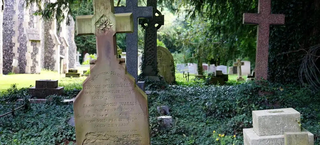 Gravestones and crosses in a quiet cemetery with green trees