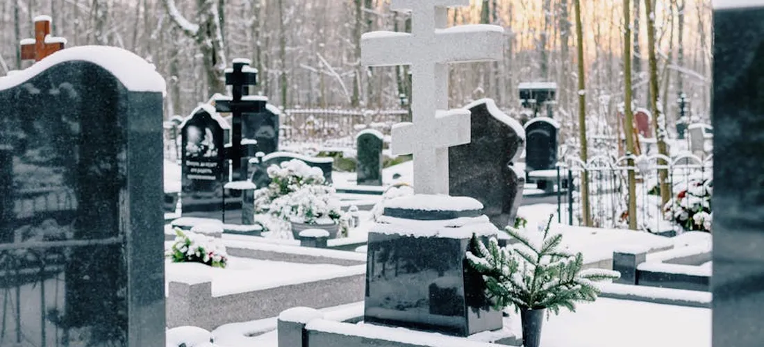 Snow-covered gravestones in a quiet cemetery, illustrating the financial and logistical considerations of indigent burial.