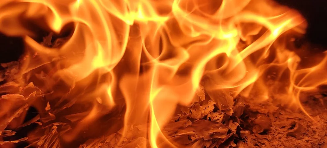Close-up of orange flames and glowing embers inside a cremation chamber