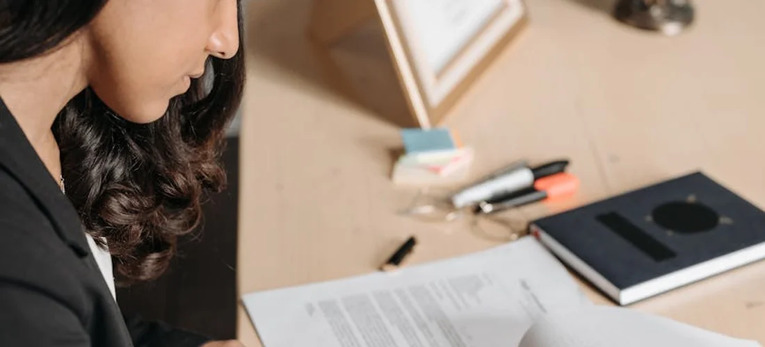 A professional reviews documents at a desk with forms, a notebook, and stationery, preparing to file a death benefit claim.