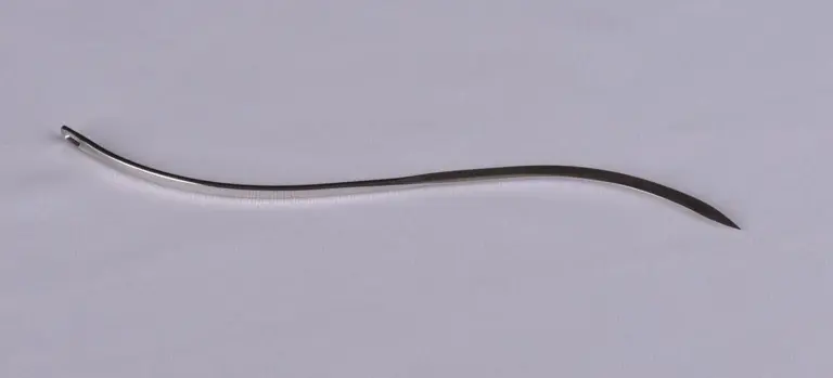 Curved stainless steel embalming tool on a pale surface